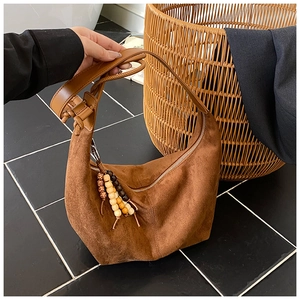 Detail der braunen Wildleder-Hobo-Tasche mit ethnischen Holzperlenquasten und Gurt