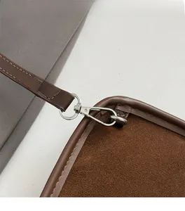 Detail of silver metal clasp and neat stitching on dark brown suede shoulder bag
