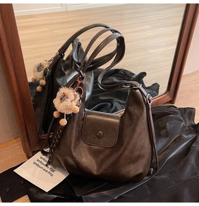 Detail of dark brown matte tote bag with cute plush lion charm reflecting in a mirror