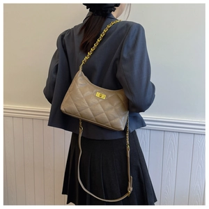 Detailed view of khaki quilted dumpling bag with gold chain strap and turn-lock closure
