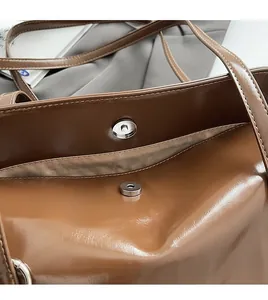 Detail shot of the silver magnetic clasp closure on a brown leather tote handbag