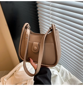 Close-up of minimalist milk tea leather hobo bag with lychee grain texture and buckled strap