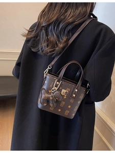 Classic brown bucket bag with teddy print and bear charm on stylish black coat model