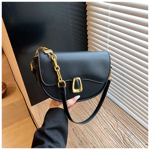Detail of black matte leather saddle bag featuring a U-shaped gold buckle and chain strap