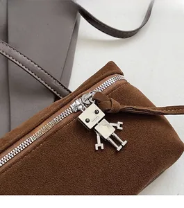 Detail of suede crossbody bag showing smooth silver zipper and cute robot metal charm puller