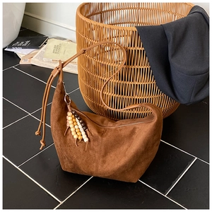 Nahaufnahme der dunkelbraunen Wildleder-Beuteltasche mit Holzperlen-Anhänger-Detail