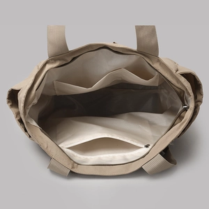 Top view of large khaki tote bag interior featuring zipper pocket and open compartments
