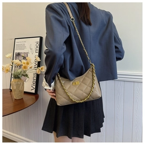 Detailed close-up of khaki quilted crossbody bag with gold chain strap and metal lock