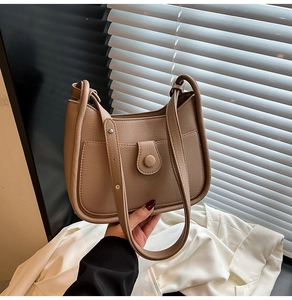 Detail of lychee pattern leather shoulder bag with flap buckle and front pocket detail