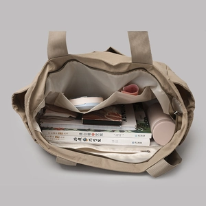 Top view of spacious khaki tote bag interior showing multi-pocket storage for books and bottle