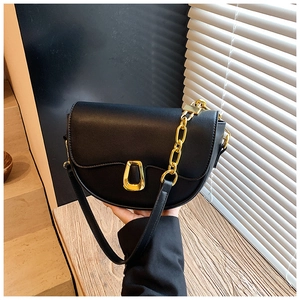 Detail of black leather saddle bag with gold geometric buckle and chain strap
