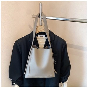 Detail of grey lychee leather bucket bag featuring a hanging decorative strap design