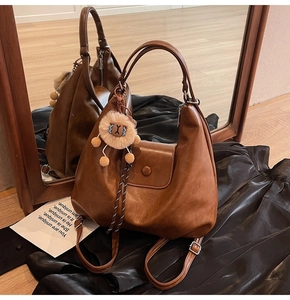 Detail of a brown faux leather tote bag with mirror reflection and a cute lion charm