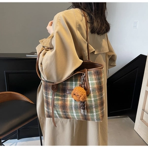 Détail du sac cabas en tweed à carreaux avec pendentif chiot peluche et lanière cuir
