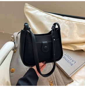 Detailed shot of a black pebble grain leather underarmpit bag on a grey blazer showing texture