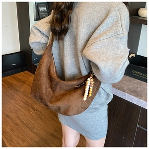 Detailansicht einer braunen Wildleder-Hobo-Tasche mit Holzperlen-Quaste am Casual-Model