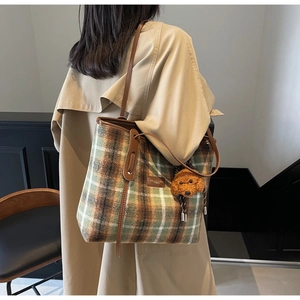 Détail du sac fourre-tout en laine à carreaux verts avec pendentif ours en peluche