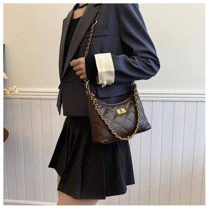 Detail of dark brown quilted crossbody bag with gold chain strap and metal turn-lock clasp