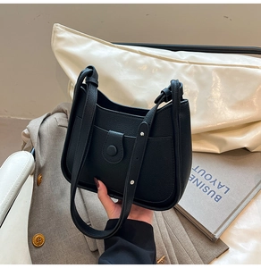 Detail of black lychee grain leather bucket bag with metallic rivet and front flap pocket