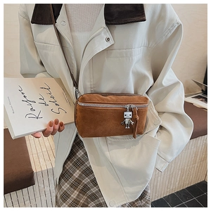 Close-up of brown suede crossbody bag with silver robot charm and metal zipper detail