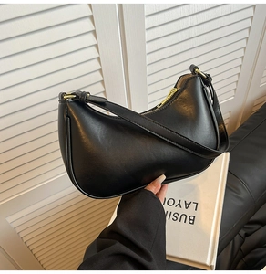 Detail shot of black leather hobo bag featuring golden zipper and adjustable shoulder strap