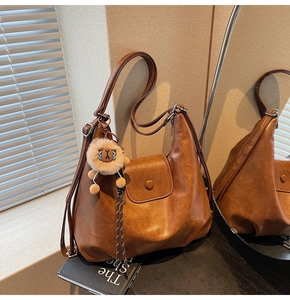 Close-up of brown PU leather tote bag featuring a cute lion plush charm and magnetic flap