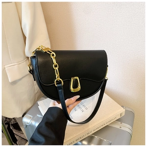 Detail of black saddle bag with thick gold chain handle and metallic trapezoidal buckle