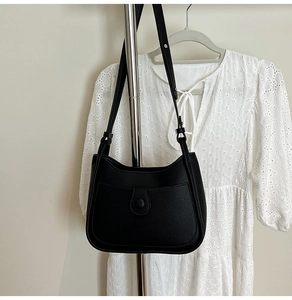 Detail of minimalist black hobo bag with pebble leather texture on a metal stand