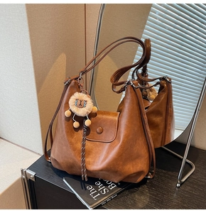 Detailed macro view of vintage brown leather tote bag with magnetic flap and plush charm
