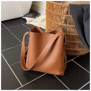 Detailed view of the brown lychee pattern leather bucket bag with wide shoulder strap