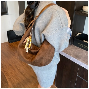 Braune Wildleder Hobo-Tasche mit Perlenanhänger in der Rückansicht am Model getragen