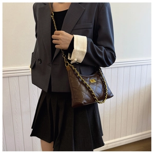 Detail view of brown quilted leather bag with gold chain strap worn on shoulder