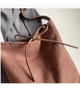 Detail of the caramel brown suede tote bag with a stylish leather bow tie closure