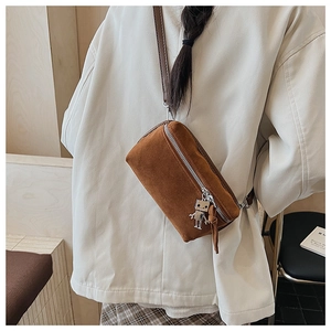 Brown suede crossbody bag with robot charm and leather tassel shown on a model