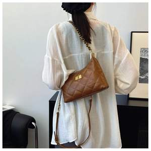 Detail of a brown quilted dumpling bag with gold chain strap worn over a white shirt