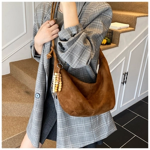 Detail einer braunen Wildleder-Hobotasche mit bunten Perlen zu einem grauen Karo-Blazer