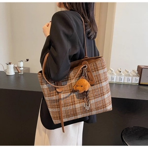 Détail du sac cabas à carreaux avec charm chien en peluche et anses en cuir brun au café