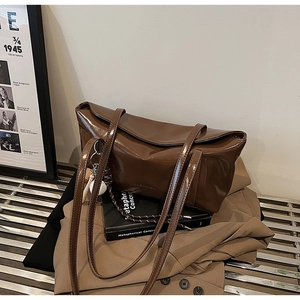 Detailed close-up of dark brown glossy patent leather tote bag on vintage background