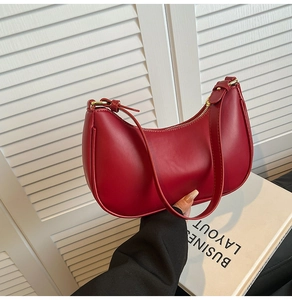Deep red crescent underarm bag with matte finish and adjustable gold metal buckle detail