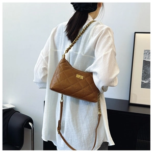 Brown quilted crossbody bag with gold chain strap worn by model against a minimalist background
