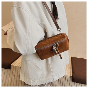 Detailed close-up of brown suede crossbody bag with unique silver robot charm