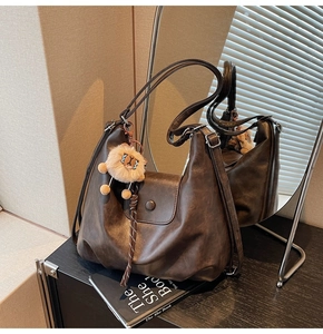 Detail view of a vintage dark brown tote bag with matte leather texture and lion charm