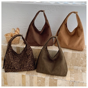 Assorted vintage leopard print and solid suede tote bags on a beige stone display
