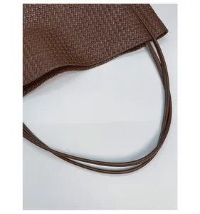 Vue macro détaillée de la texture tressée marron foncé et des fines poignées du sac cabas