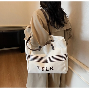 Detailed view of the TELN canvas tote bag showing large capacity and brown stripe accents
