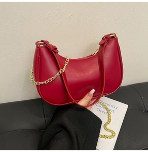 Detail view of red crescent moon shoulder bag featuring golden chain and smooth PU leather