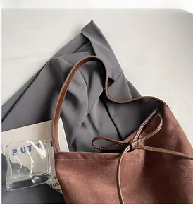 Detail of a brown frosted tote bag showing slender dark brown leather straps and bow drawstring