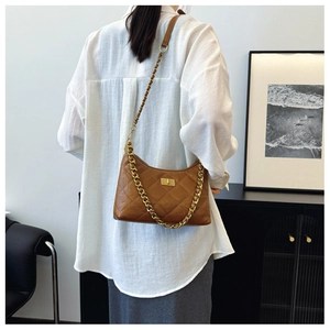 Detail of a brown quilted hobo bag featuring a gold twist lock and woven chain strap