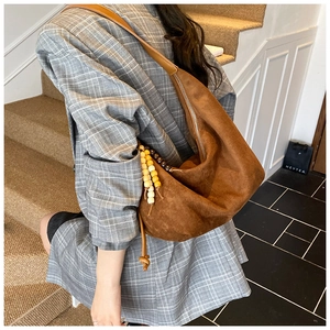 Makro-Detail der dunkelbraunen Hobo-Tasche aus Wildleder mit Holzperlen und Reißverschluss