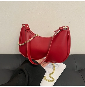 Detail of red PU leather half-moon bag with gold chain strap and zipper closure